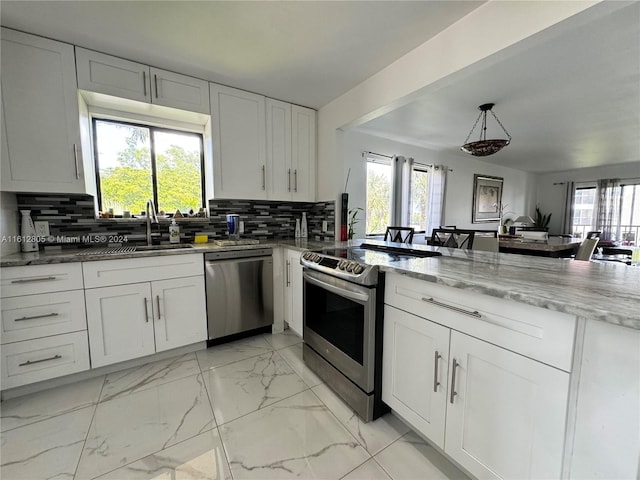 kitchen featuring appliances with stainless steel finishes, white cabinetry, tasteful backsplash, and light tile flooring