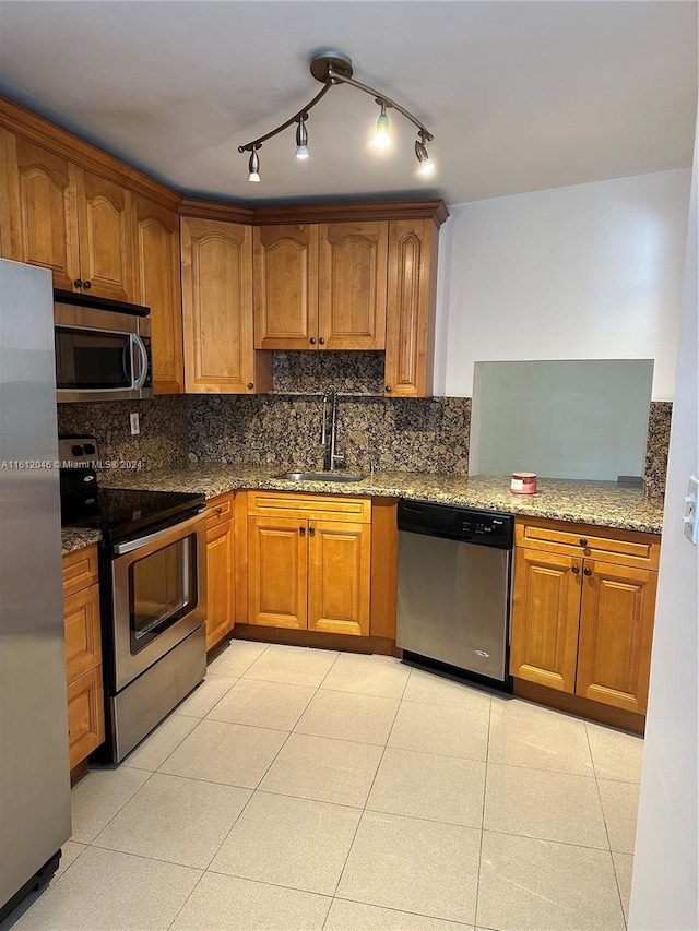 kitchen featuring sink, stainless steel appliances, light stone counters, backsplash, and light tile patterned floors