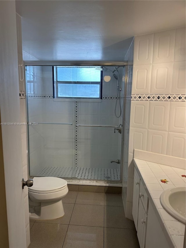 bathroom with tile patterned flooring, vanity, toilet, and walk in shower