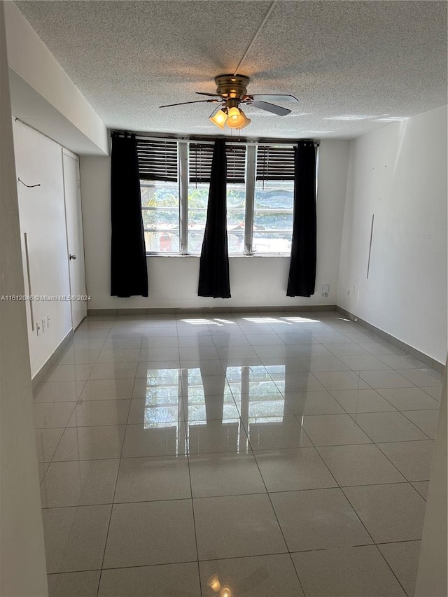 spare room with ceiling fan and light tile patterned flooring