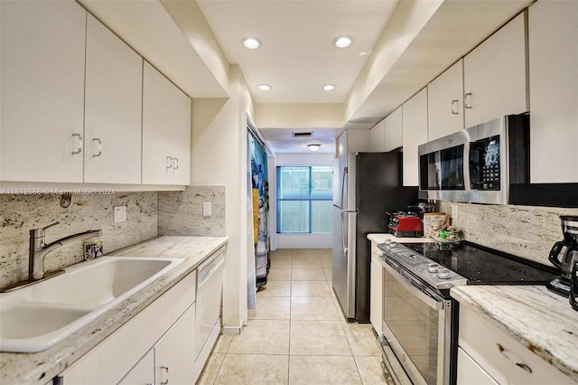 kitchen with backsplash, white cabinets, sink, light tile patterned floors, and appliances with stainless steel finishes