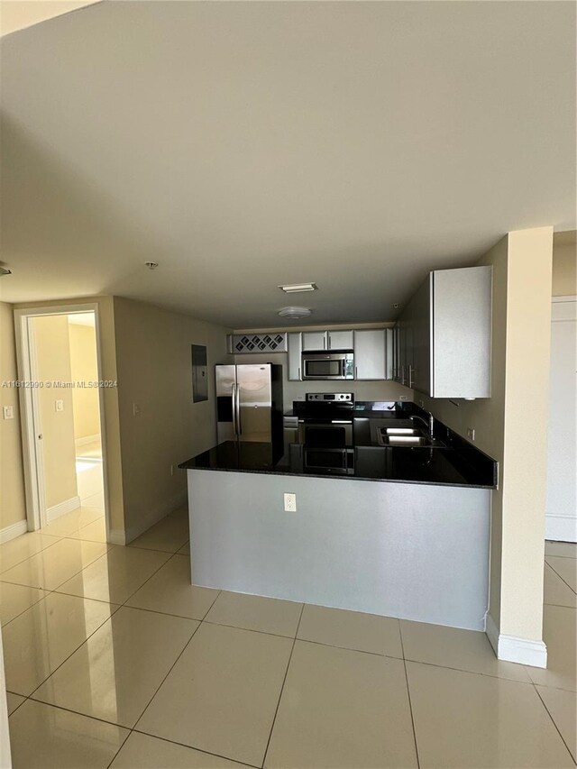 kitchen featuring stainless steel appliances, light tile floors, and kitchen peninsula