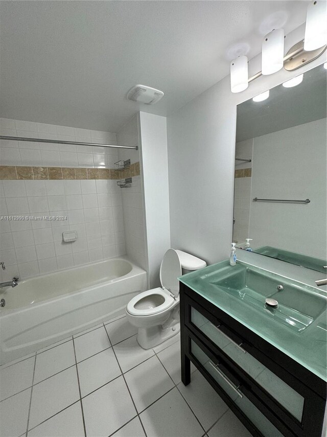 full bathroom with tile floors, vanity, toilet, and tiled shower / bath combo