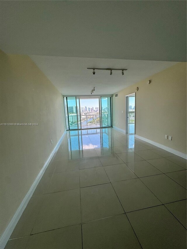 tiled spare room featuring expansive windows and rail lighting