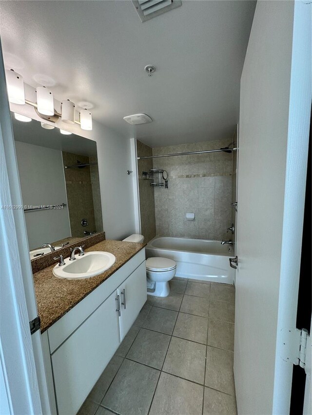 full bathroom with tiled shower / bath, tile flooring, oversized vanity, and toilet