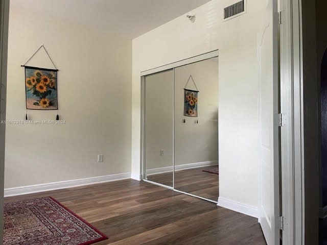 unfurnished bedroom with dark hardwood / wood-style floors and a closet