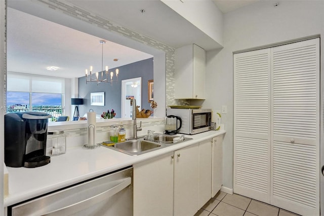 kitchen with sink, dishwasher, white cabinetry, hanging light fixtures, and light tile patterned flooring