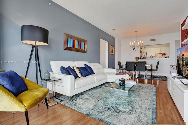 living room with light hardwood / wood-style floors and an inviting chandelier