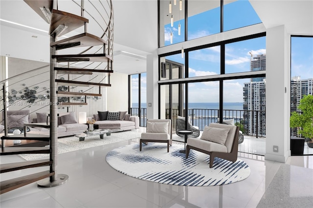 living room featuring a water view, light tile patterned floors, a wealth of natural light, and a towering ceiling