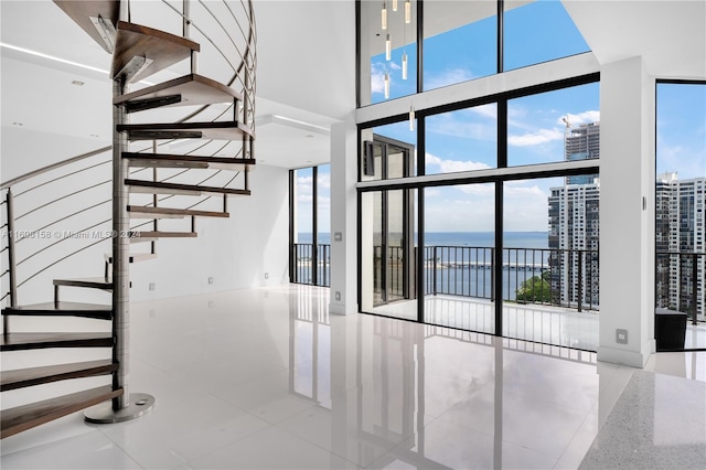 staircase featuring tile patterned flooring, a water view, and a wall of windows