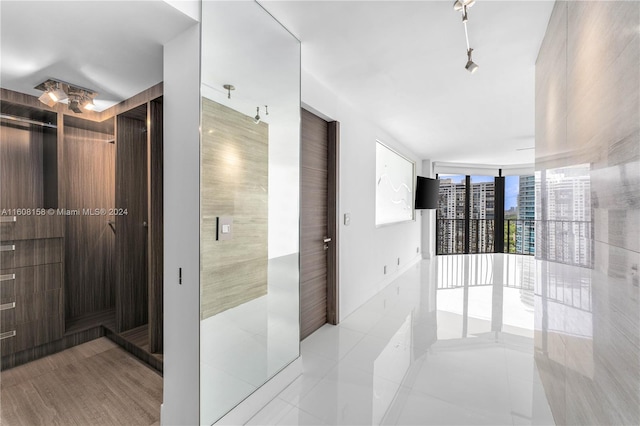 corridor featuring light tile patterned flooring and a wall of windows