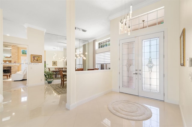 foyer featuring ornamental molding, french doors, light tile floors, and a chandelier