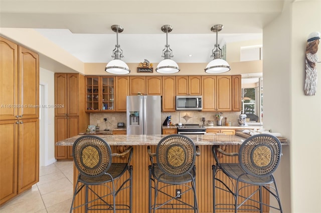 kitchen featuring light tile flooring, stainless steel appliances, backsplash, hanging light fixtures, and a center island