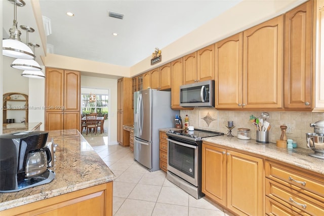 kitchen featuring stainless steel appliances, light stone counters, backsplash, light tile floors, and hanging light fixtures