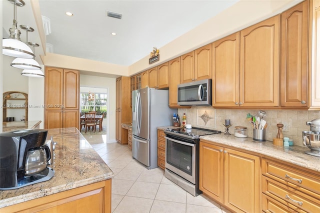 kitchen featuring light stone counters, decorative backsplash, appliances with stainless steel finishes, and hanging light fixtures