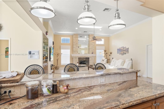 kitchen with pendant lighting, a healthy amount of sunlight, ornamental molding, and light stone countertops