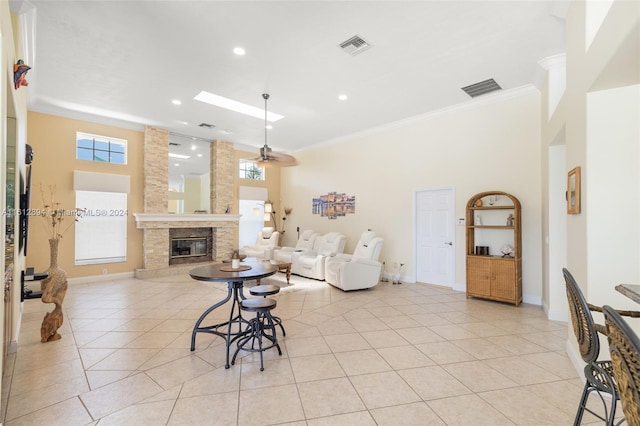 tiled living room featuring crown molding, a large fireplace, plenty of natural light, and a towering ceiling