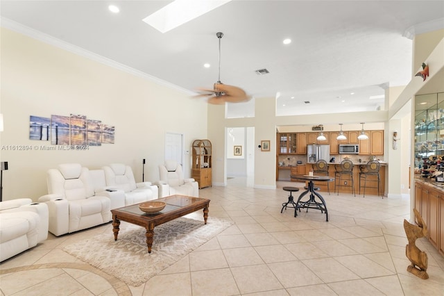 tiled living room with a high ceiling, crown molding, ceiling fan, and a skylight