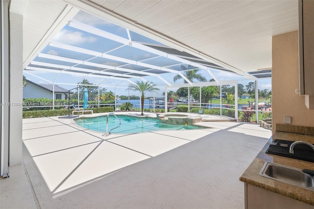 view of swimming pool with a patio, a lanai, sink, and an in ground hot tub