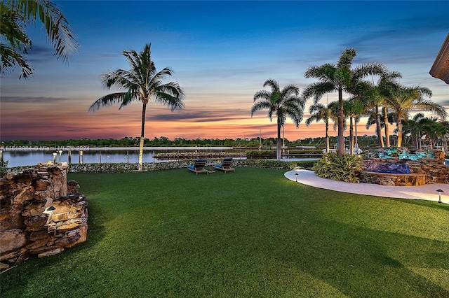 yard at dusk featuring a water view