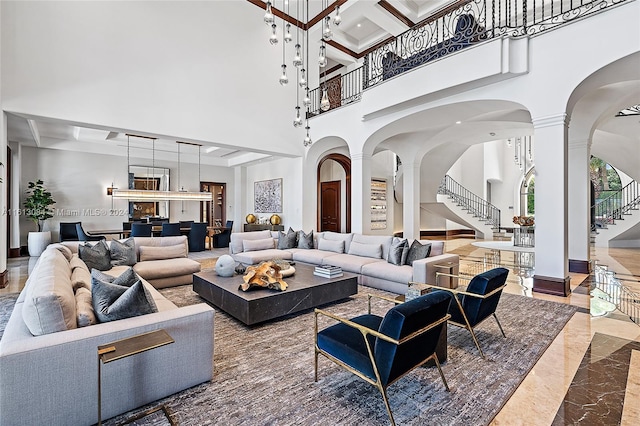 living room with beamed ceiling, a towering ceiling, decorative columns, and coffered ceiling