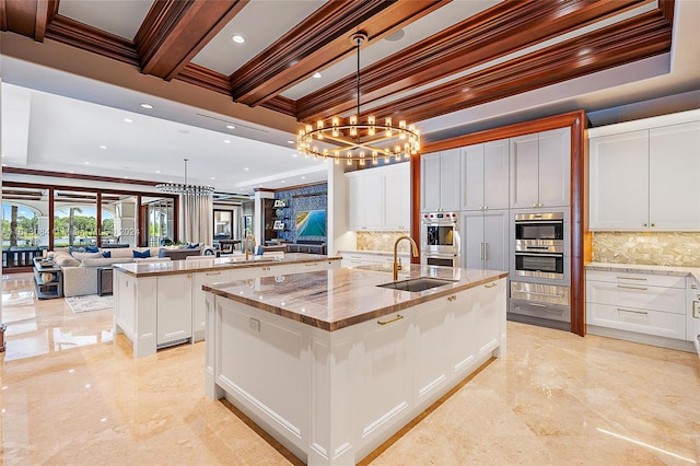 kitchen featuring pendant lighting, a large island, white cabinetry, and sink