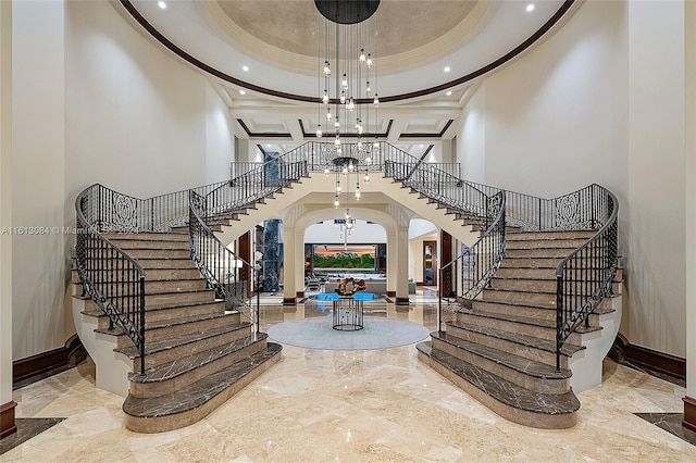 foyer featuring a towering ceiling, ornate columns, and coffered ceiling