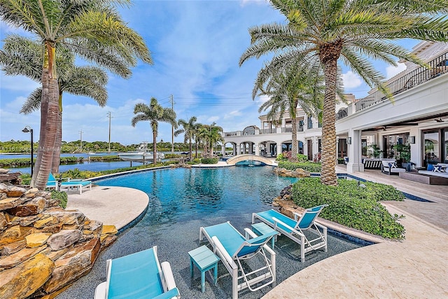 view of pool with a water view and a patio