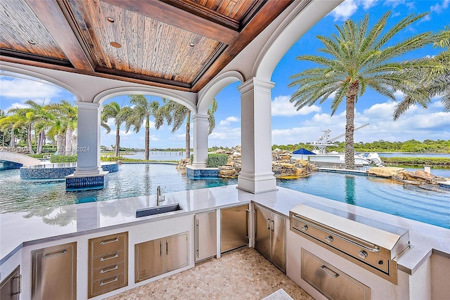 view of patio / terrace featuring area for grilling, a water view, and sink