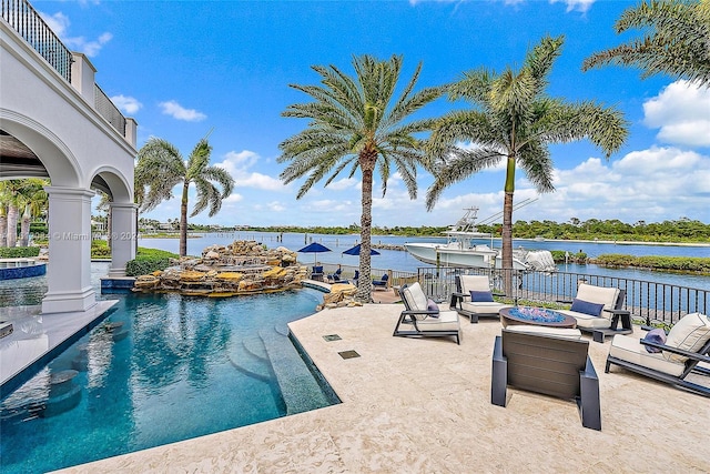 view of swimming pool featuring a water view, a patio, and an outdoor fire pit