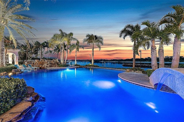 pool at dusk with pool water feature and a water view