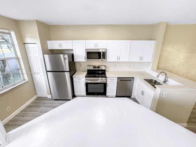 kitchen with white cabinetry, sink, stainless steel appliances, and light hardwood / wood-style flooring