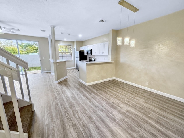 kitchen featuring pendant lighting, kitchen peninsula, light hardwood / wood-style flooring, appliances with stainless steel finishes, and white cabinetry