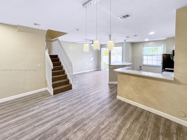 kitchen with black fridge, sink, hanging light fixtures, and hardwood / wood-style flooring