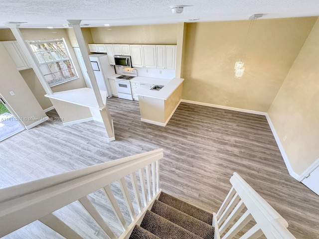 stairs featuring wood-type flooring and a textured ceiling