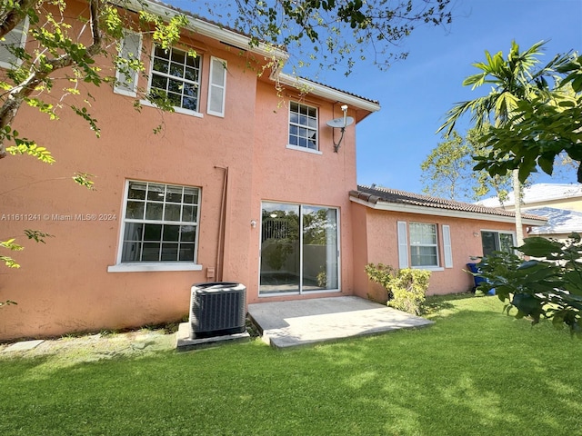 rear view of property with a yard, a patio, and central AC