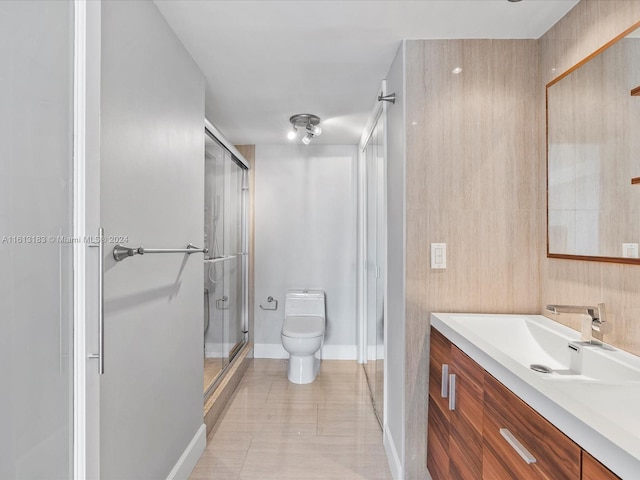 bathroom with an enclosed shower, tile flooring, vanity, and toilet