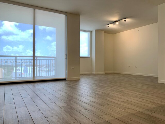 unfurnished room with track lighting and light hardwood / wood-style flooring