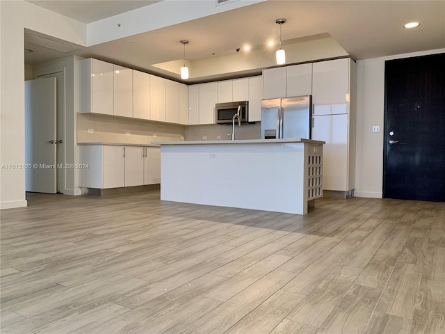 kitchen with white cabinetry, hanging light fixtures, light wood-type flooring, and appliances with stainless steel finishes