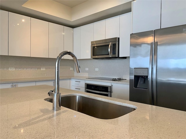 kitchen with white cabinetry, tasteful backsplash, stainless steel appliances, and light stone counters