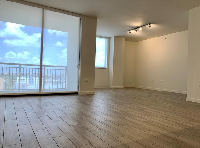 spare room featuring track lighting and light hardwood / wood-style flooring