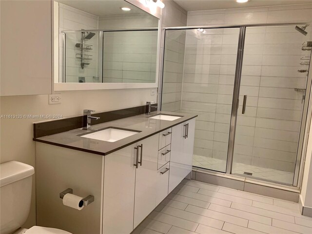 bathroom featuring tile floors, a shower with shower door, toilet, and large vanity