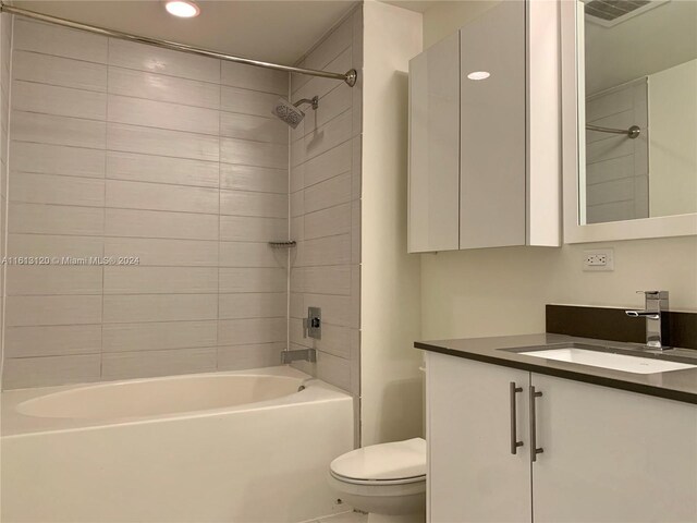 full bathroom featuring tiled shower / bath, toilet, and vanity with extensive cabinet space