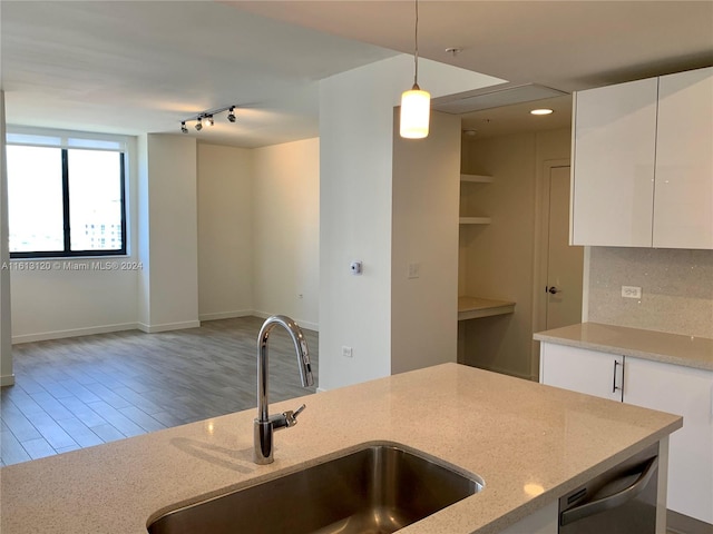 kitchen featuring white cabinets, backsplash, light stone countertops, and rail lighting