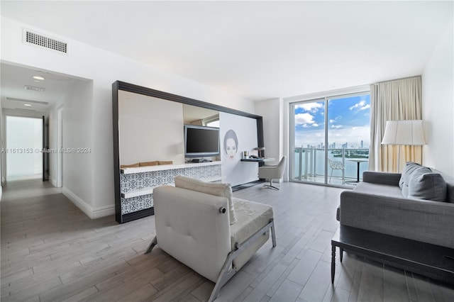 living room with hardwood / wood-style floors, expansive windows, and a water view