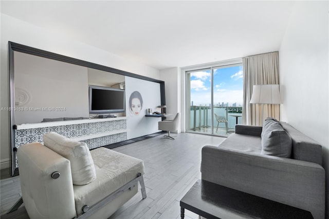 living room featuring floor to ceiling windows, a water view, and hardwood / wood-style floors