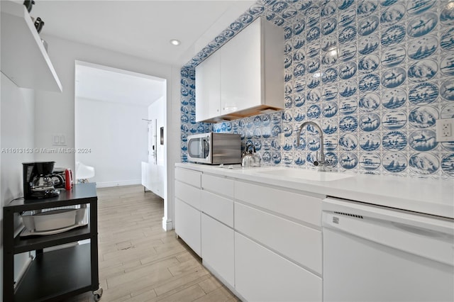 kitchen featuring light hardwood / wood-style flooring, backsplash, white dishwasher, sink, and white cabinetry