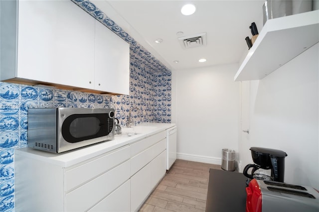 kitchen with sink, white cabinetry, white dishwasher, and light wood-type flooring