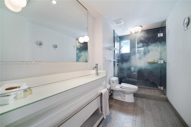 bathroom with a shower with shower door, toilet, and vanity