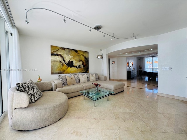 living room with baseboards, arched walkways, and track lighting